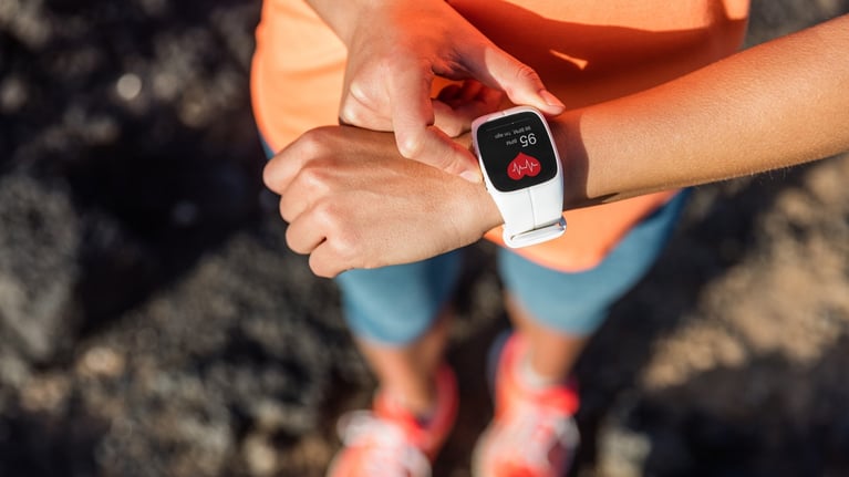 Persona usando un reloj inteligente en la muñeca que muestra frecuencia cardíaca, monitoreo de salud cardiovascular en actividad física