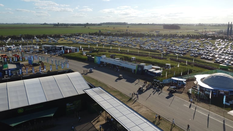 Vista aérea de Expoagro con stands, maquinaria agrícola, estacionamiento y visitantes, evento del sector agropecuario con enfoque en innovación y producción
