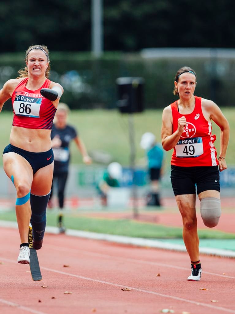 Two athletes running on a track during a sports event, representing Bayer’s commitment to sports sponsorships and athletic participation.