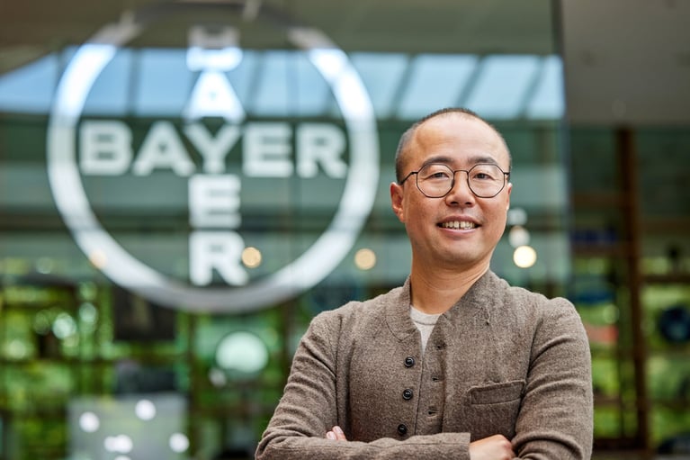 employee in front of a bayer cross 8 1