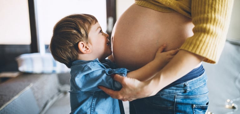Niño pequeño abraza el vientre de una persona embarazada, salud prenatal y desarrollo del bebé durante el embarazo