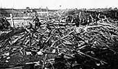 Imagem histórica em preto e branco mostrando um campo de batalha devastado durante a Primeira Guerra Mundial, com solo destruído, troncos quebrados e destroços espalhados, simbolizando o impacto do conflito no período da Bayer entre 1914 e 1925.