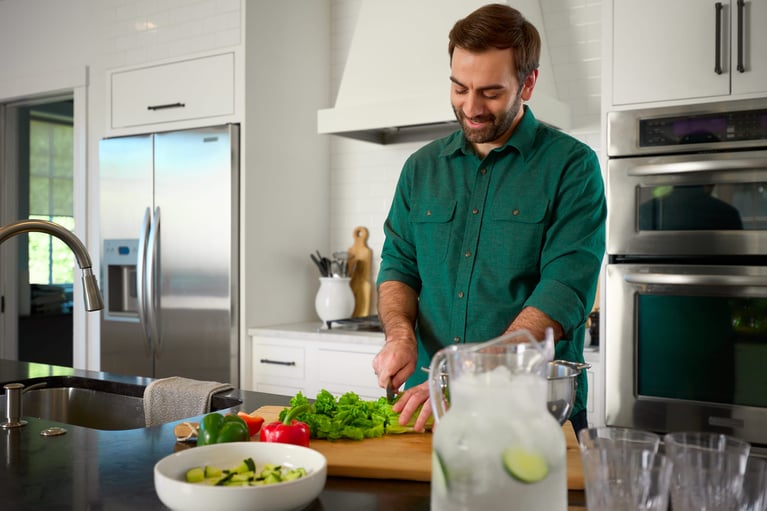 Persona preparando alimentos frescos en la cocina sobre una tabla de cortar, hábitos saludables y alimentación equilibrada para fortalecer el sistema inmune