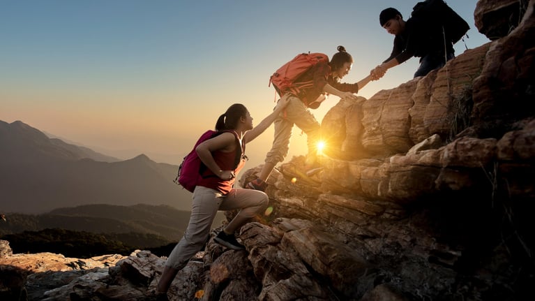 asian hikers helping each other