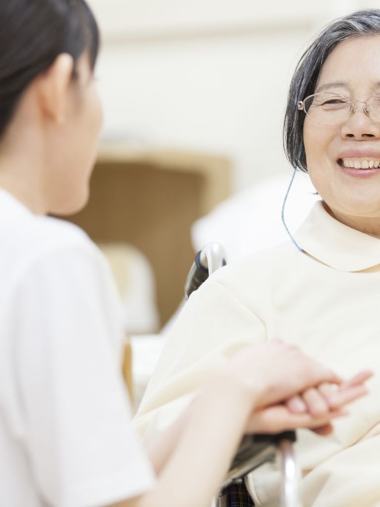 nurse touching patient_s hand in wheelchair.jpeg