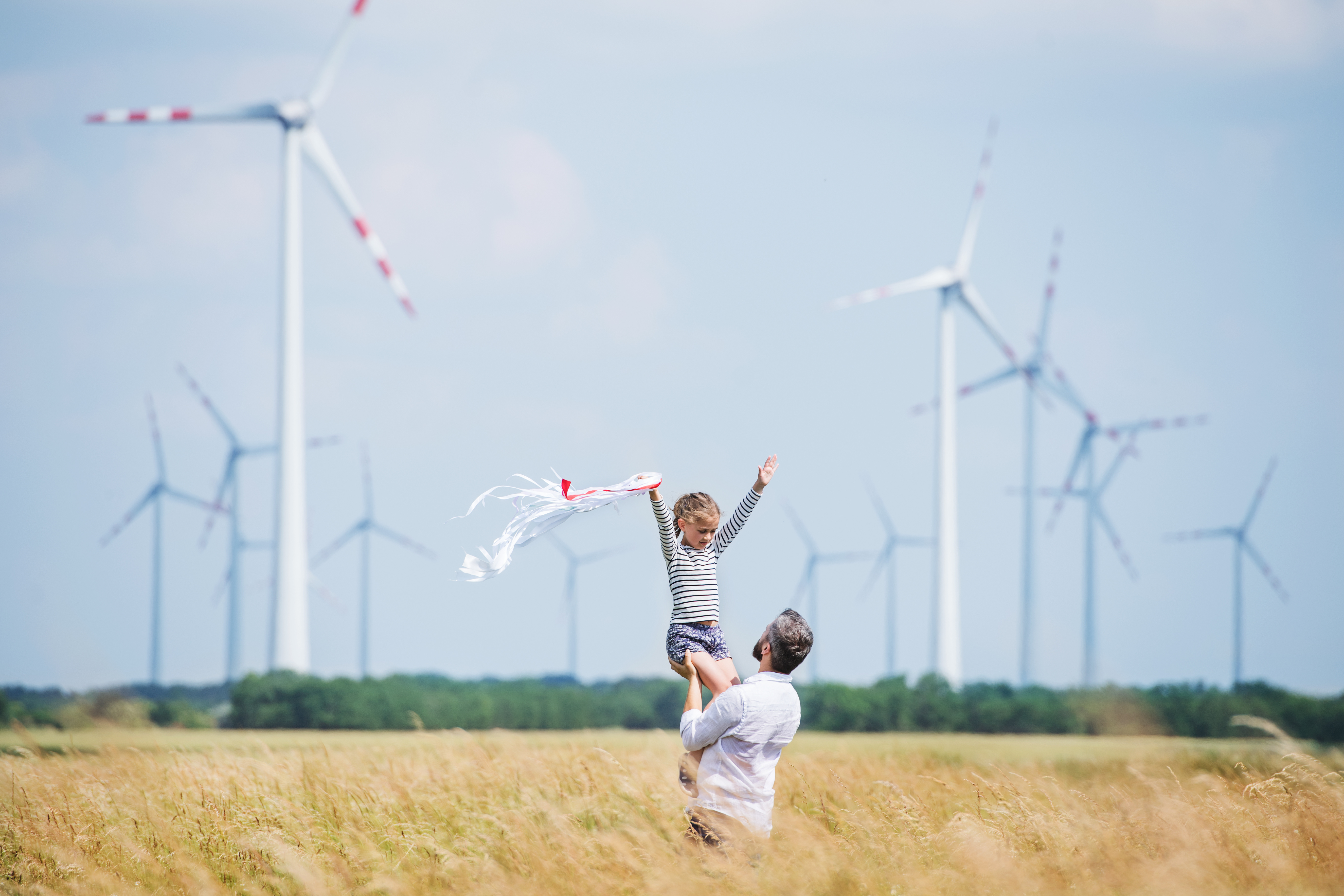 father_and_daughter_in_front_of_wind_farm.jpeg