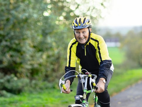 Persona montando una bicicleta al aire libre con casco, actividad física y estilo de vida saludable relacionado con la salud cardiovascular