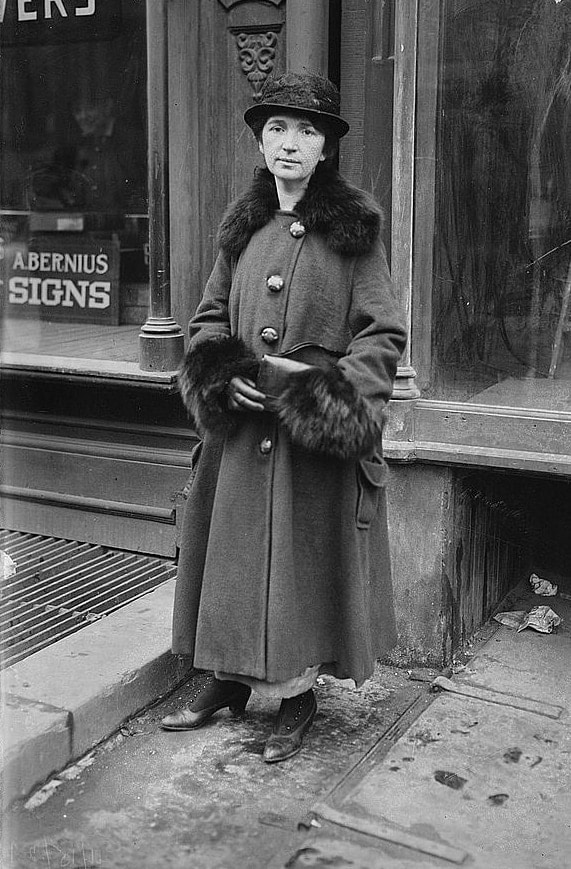 Retrato histórico de Margaret Sanger, activista por los derechos reproductivos, con abrigo largo y sombrero.