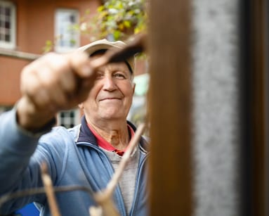 Persona utilizando una herramienta en una puerta o superficie metálica, actividad manual en entorno doméstico o laboral relacionado con la salud cardiovascular