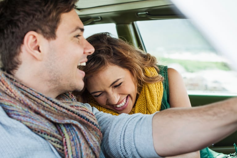 Una pareja joven en un coche; la mujer se inclina hacia él mientras ríen, en el contexto del uso de anticonceptivos