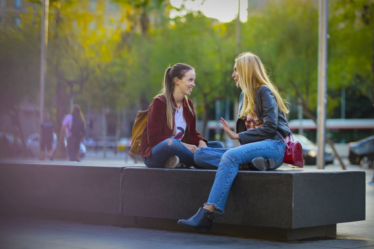 Dos personas sentadas al aire libre conversando en un entorno urbano, intercambio de información y toma de decisiones informadas sobre salud sexual y métodos anticonceptivos