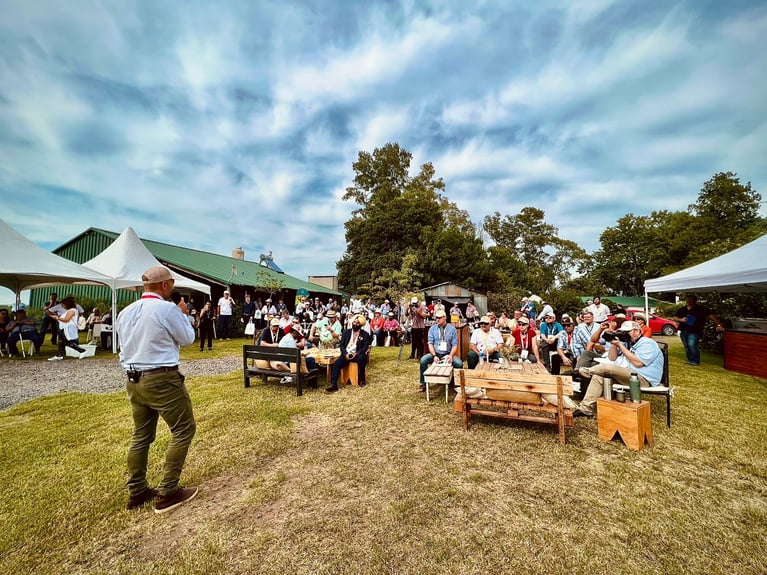 Grupo de personas reunidas en jornada agrícola al aire libre con carpas y presentaciones, intercambio de conocimiento y prácticas sostenibles en el marco de Bayer ForwardFarming