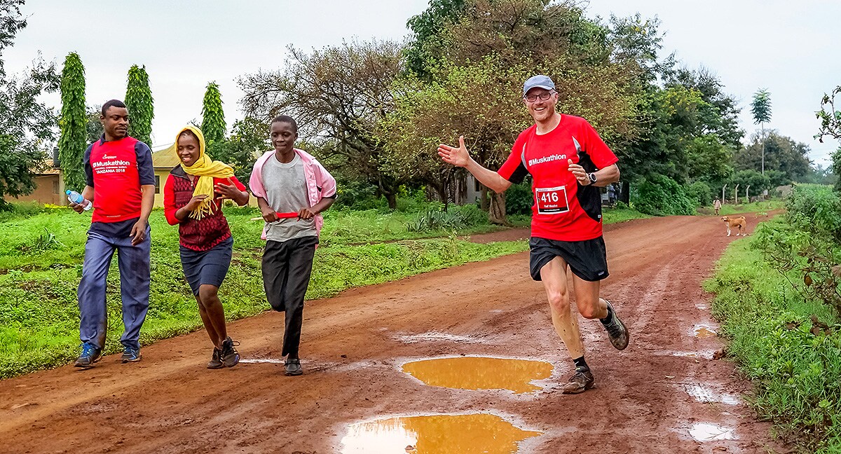 A group of people run down a dirt road.