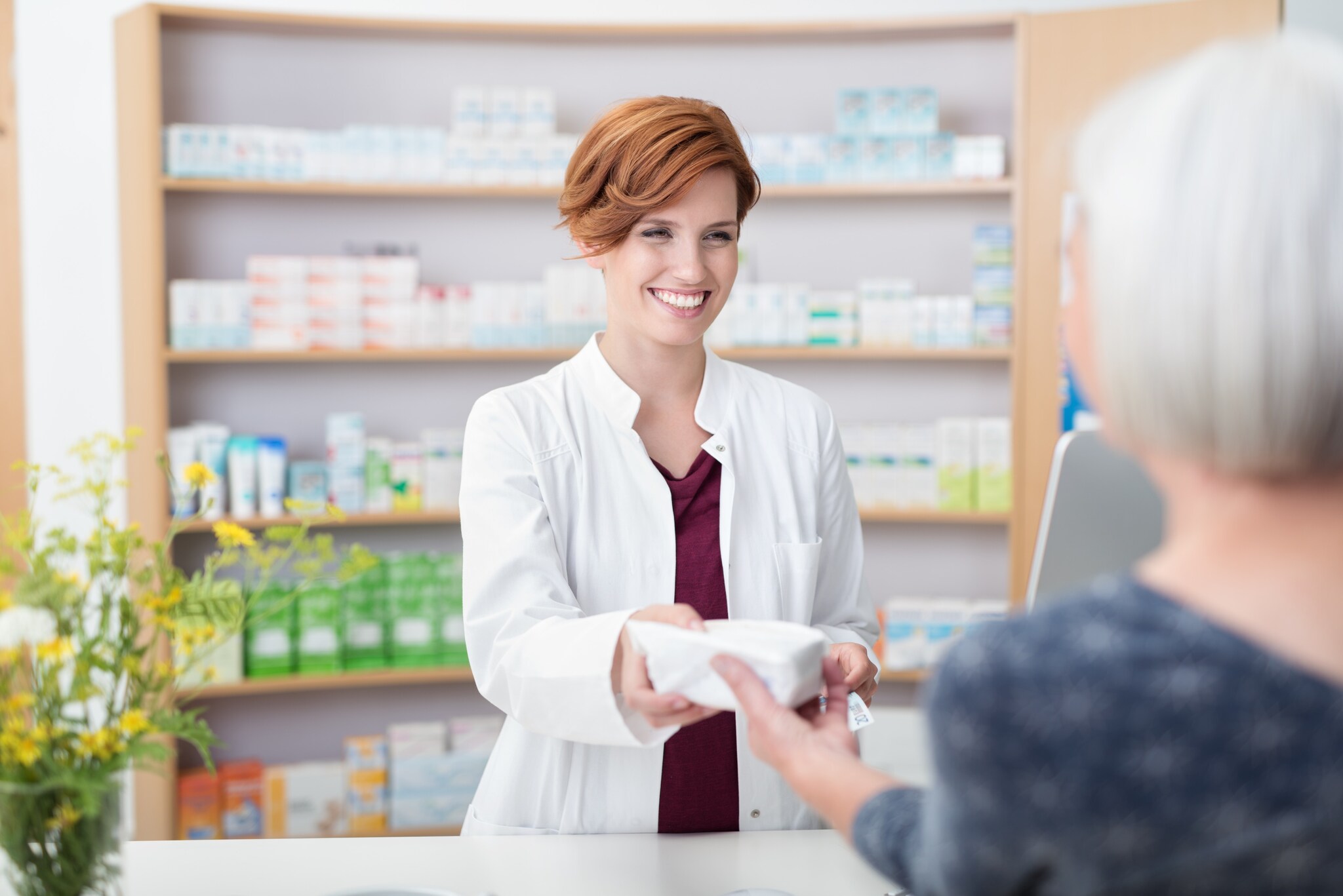 A phlebotomist is handing a patient a medicine.