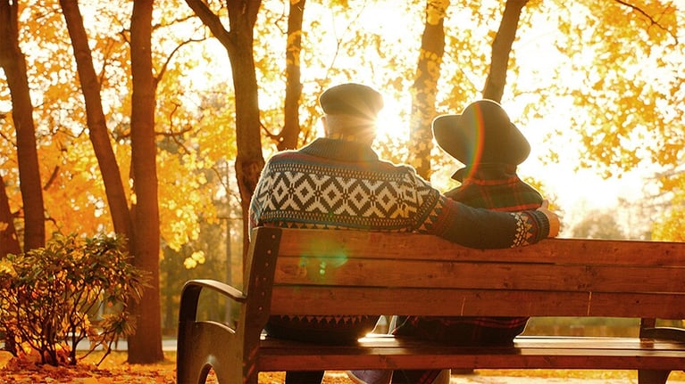 Pareja adulta sentada al aire libre en un parque, bienestar y calidad de vida en el contexto de la concientización sobre la salud masculina y el cáncer de próstata