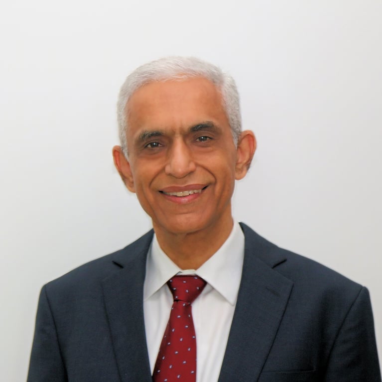 Profile photo of Ravi Kirpalani wearing a dark suit with a red tie, smiling, and posing against a plain background.