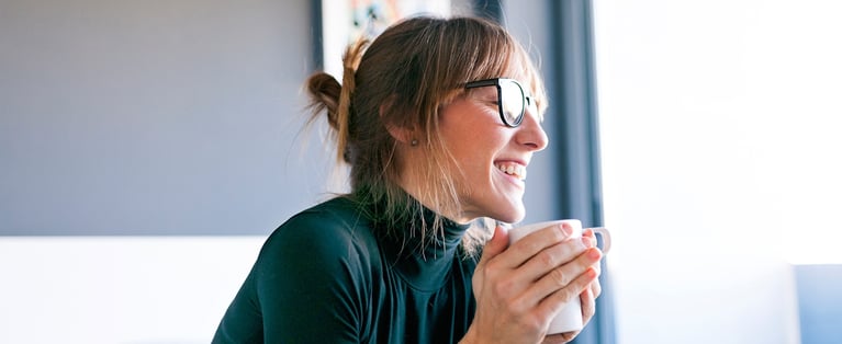 Smiling_woman_holding_coffee_cup_1440x590_1.jpg