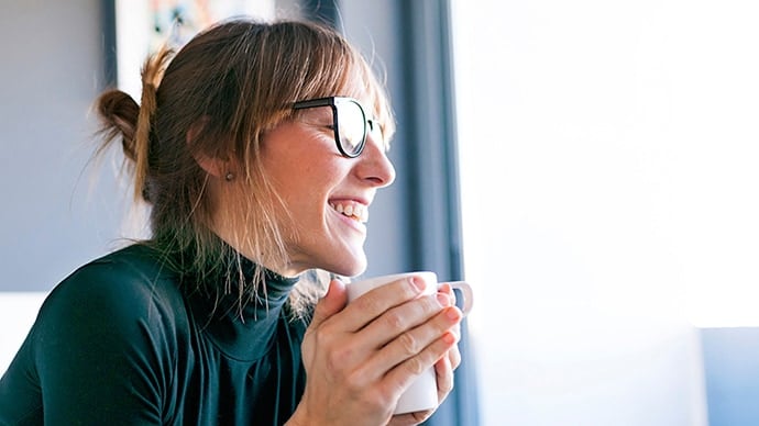 Smiling_woman_holding_coffee_cup_690x388.jpg