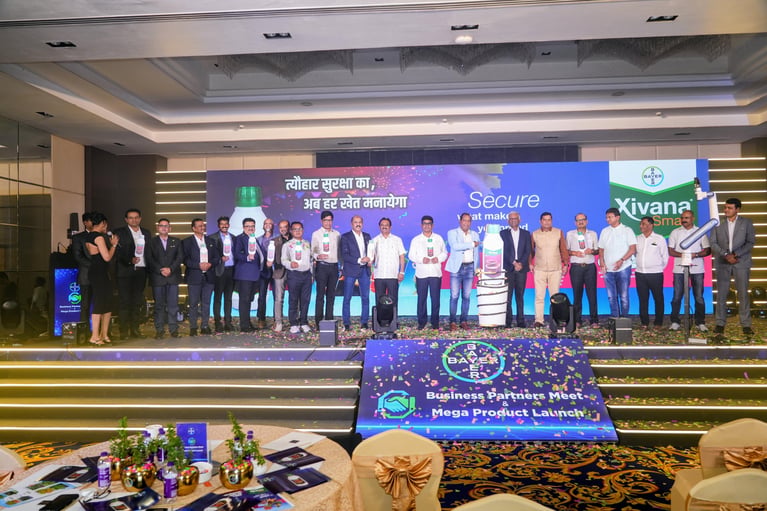 Group photo of individuals standing on a stage at a business meeting event, with a banner displaying a product launch of Xivana™ Smart.